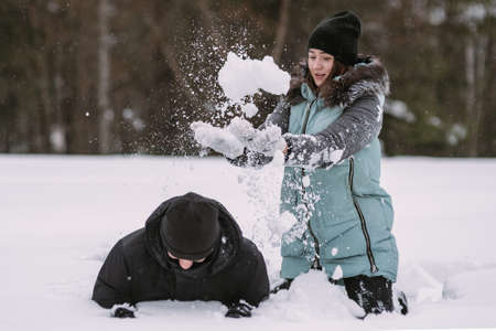 Happy couple teenagers having fun playing in snow in winter forestの写真素材