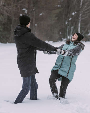 Happy couple of teenagers dancing and having fun in winter forestの写真素材