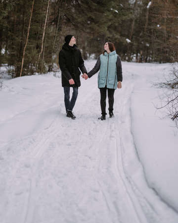 Loving couple of teenagers walking in winter forestの写真素材