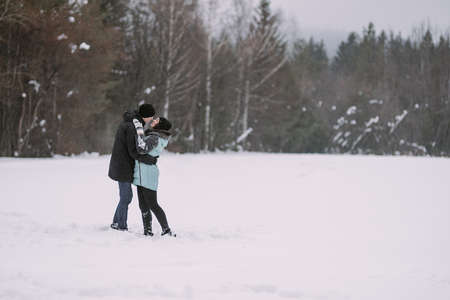 Loving couple of teenagers hugging and kissing in winter forestの写真素材