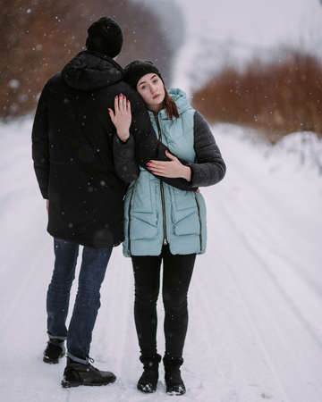 Loving couple of teenagers walking in winter forestの写真素材