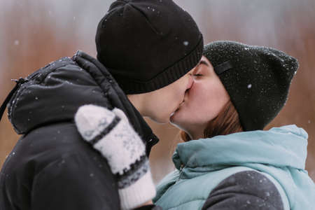 Portrait of couple of teenagers kissing in winter forestの写真素材