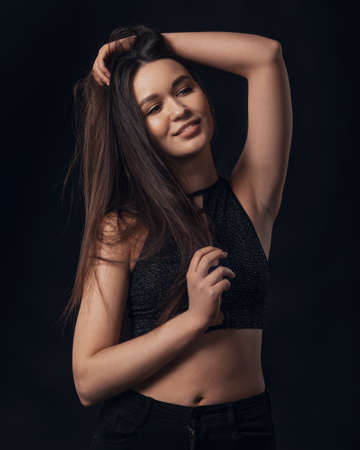 Studio portrait of pretty smiling brunette woman on black background.の写真素材