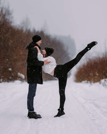 Loving couple of teenagers walking and having fun in winter forestの写真素材