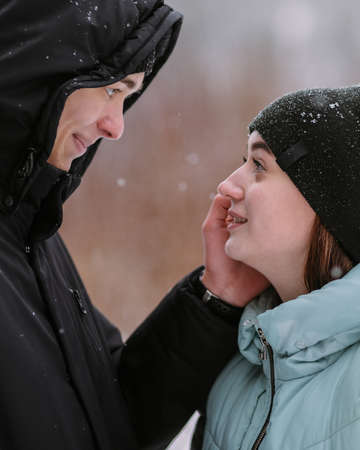 Portrait of couple of teenagers looking at each other in winter forestの写真素材