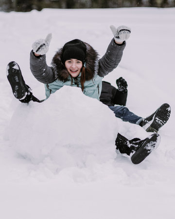 Couple of teenagers building snowman together in winter forestの写真素材