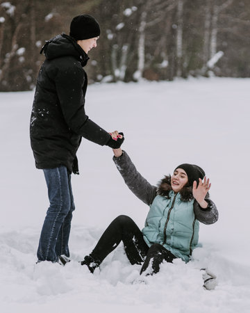 Happy couple of teenagers having fun playing in snow in winter forestの写真素材