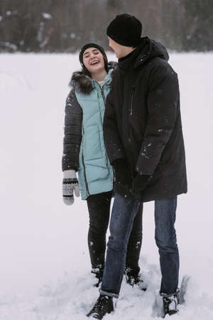 Happy couple of teenagers having fun playing in snow in winter forestの写真素材