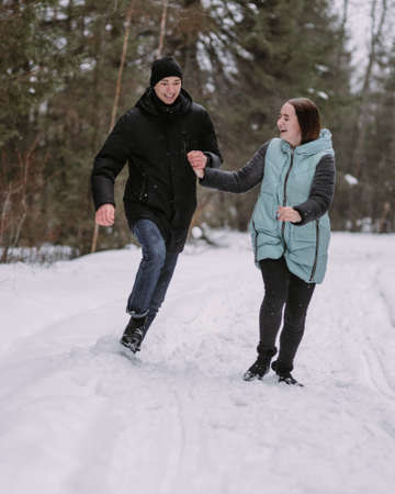 Loving couple of teenagers walking in winter forestの写真素材