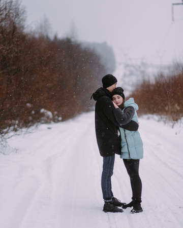 Loving couple of teenagers walking in winter forestの写真素材