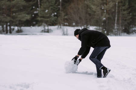 Couple of teenagers building snowman together in winter forestの写真素材