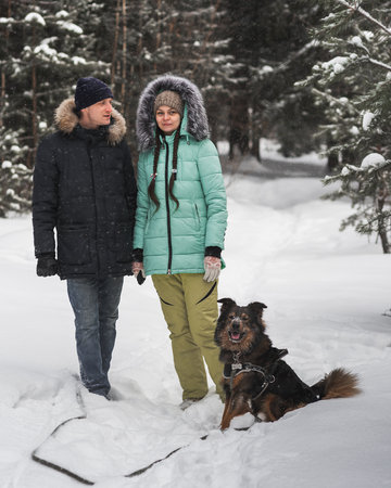 Cute couple having fun with their dog in winter forestの写真素材