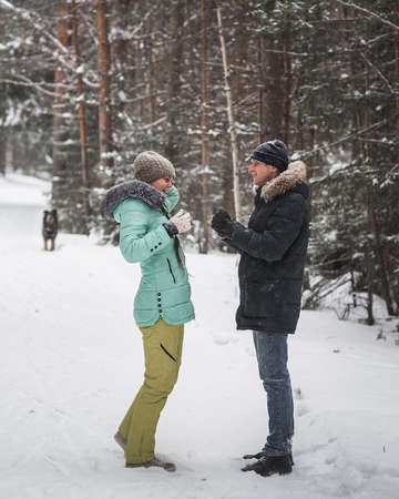 Happy young couple fun in snow and walking in forest on winter dayの写真素材