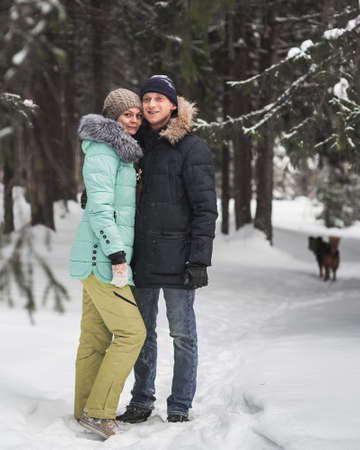Happy young couple walking in forest on winter dayの写真素材