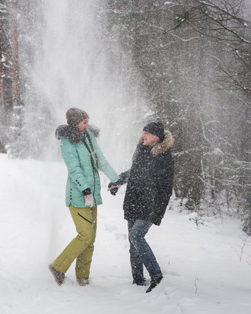 Happy young couple fun in snow and walking in forest on winter dayの写真素材