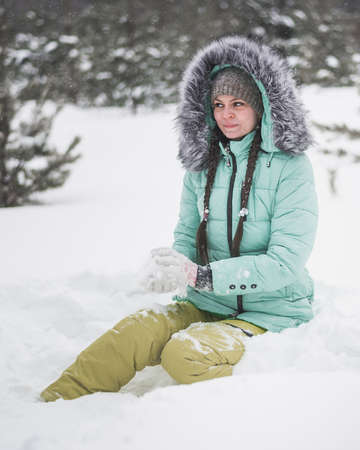 Woman having fun with dog in the snow in winter forestの写真素材