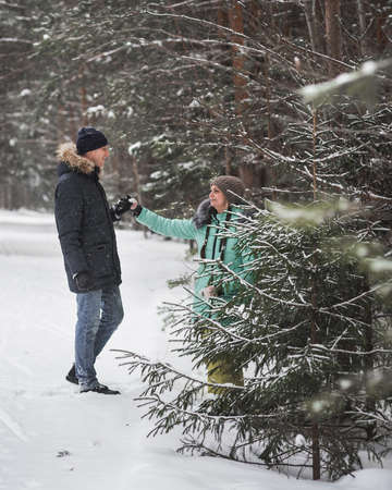 Happy young couple walking in forest on winter dayの写真素材