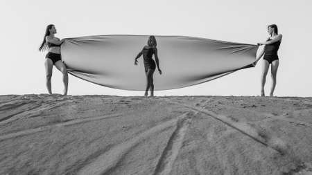 Three girls with transparent fabric on the top of sand dune. black and whiteの写真素材