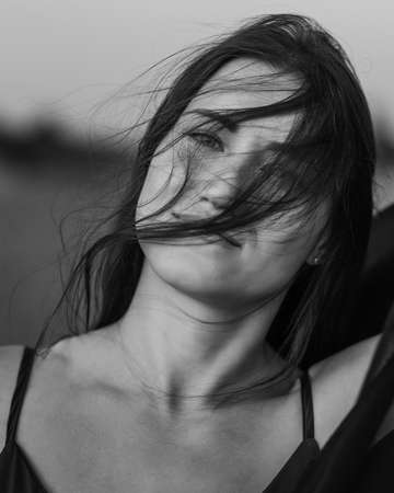 Portrait of the young woman covered flying black fabric on sand dune. black and whiteの写真素材