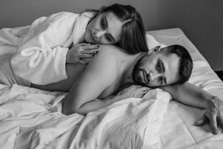 European couple hugging together while lying in bed at hotelの写真素材