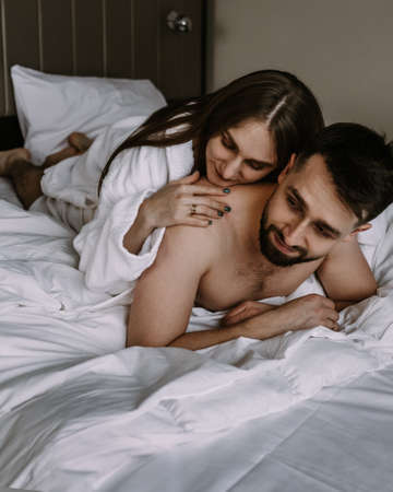 European couple hugging together while lying in bed at hotelの写真素材