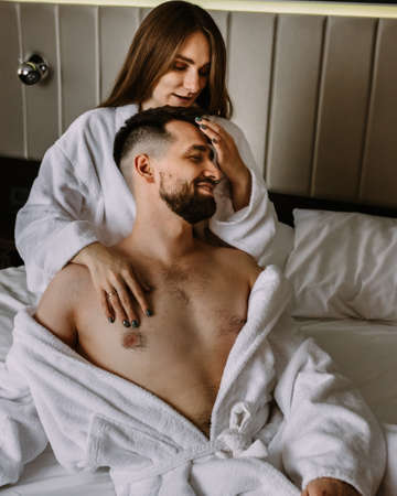 Young sexy loving couple in bathrobes relaxing on bed at hotel. black and whiteの写真素材