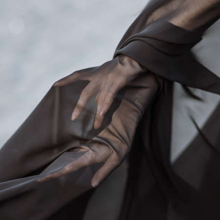 Closeup detail hands of woman under black transparent textileの写真素材