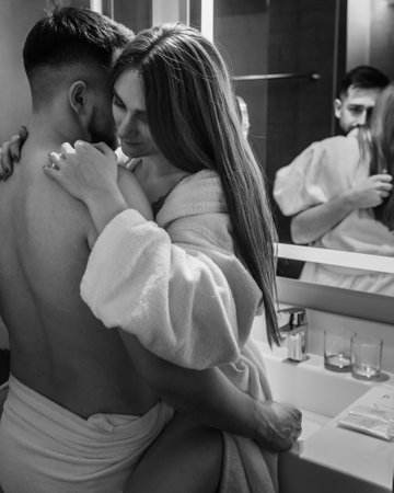 Passionate couple cuddles and kisses at mirror in bathroom, Black and whiteの写真素材