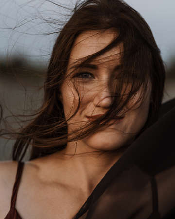 Portrait of the young woman covered flying black fabric on sand duneの写真素材