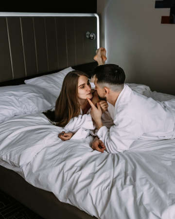 Young loving Caucasian couple kissing on bed at hotelの写真素材