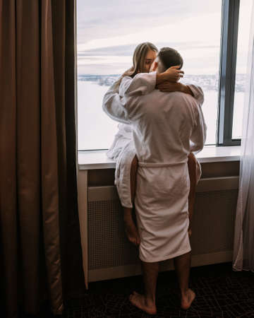 Happy beautiful couple in the hotel on window kiss and hug each otherの写真素材