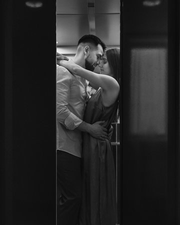 Young stylish caucasian couple hugging and kissing in hotels elevator. black and whiteの写真素材