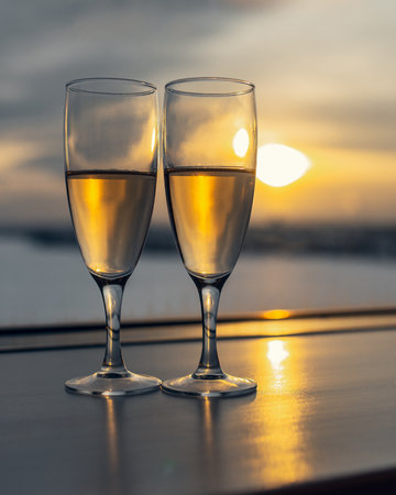 Two glasses with champagne at window on sunsetの写真素材