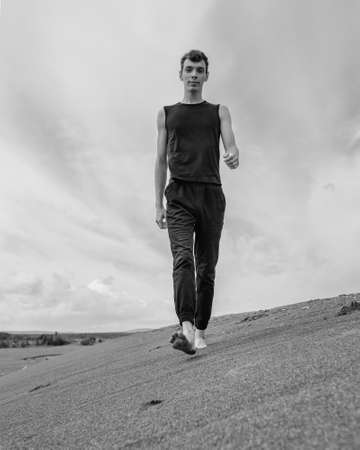 Young man walking alone on the sand in sandy desert. black and whiteの写真素材