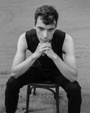 Portrait of man sitting on chair in desert. black and whiteの写真素材