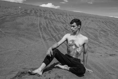 Man sitting on the sand in sandy desert. black and whiteの写真素材