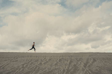 Lone man running on the sand through sandy desert on the horizonの写真素材