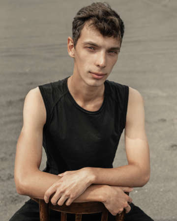 Portrait of young man sitting on chair in desertの写真素材
