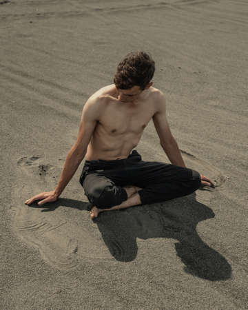 Man sitting on the sand in sandy desertの写真素材