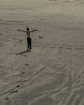 Young man walking alone on the sand in sandy desertの写真素材