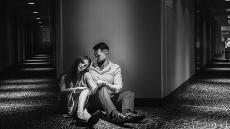 Young couple in love sitting on the floor of the corridor of the hotel. black and whiteの写真素材