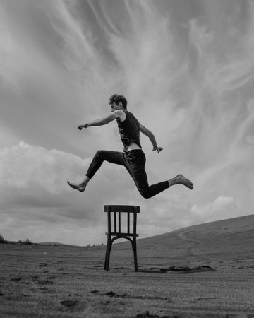 Man jumping over chair in desert. black and whiteの写真素材