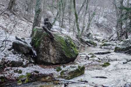 Mermaid statue on stone on the river near the waterfall Djur-Djur in early spring with snow. Crimeaの写真素材