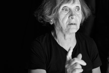 Portrait of senior caucasian woman talking on black background. Close up, black and whiteの写真素材