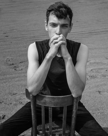 Portrait of man sitting on chair in desert. black and whiteの写真素材