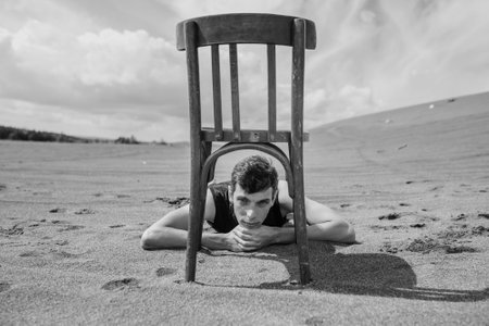 Man lying under chair in desert. black and whiteの写真素材
