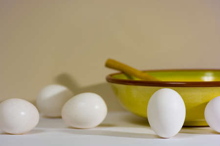 Still life photo of a cooking bowl with a wooden spoon and several eggs.  One egg is inverted symbolizing the idea of being unique, special or standing out from the crowdの写真素材