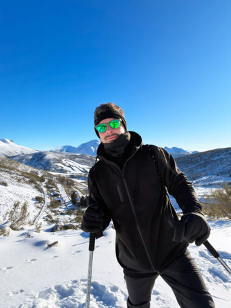 Man hiking mountains in snow on sunny day