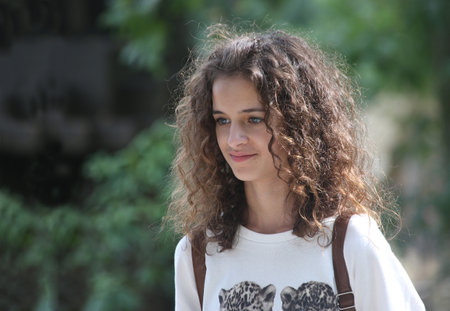 Head portrait of a young smiling brunette caucasian girl of with long curly hairのeditorial素材