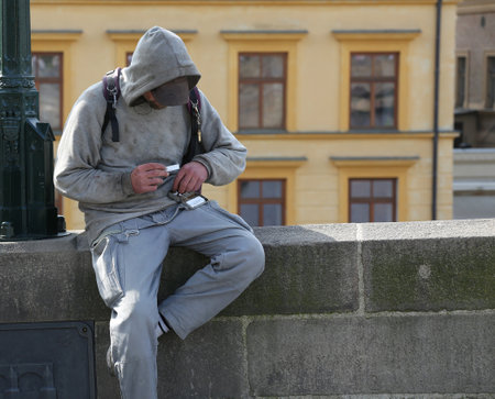 Addict man with hands sore from injections rolls up a marijuana cigaretteの写真素材